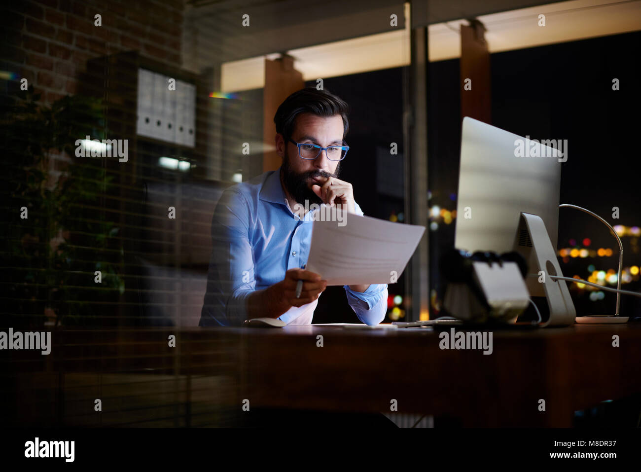 Giovane imprenditore la lettura di documenti all ufficio di notte Foto Stock