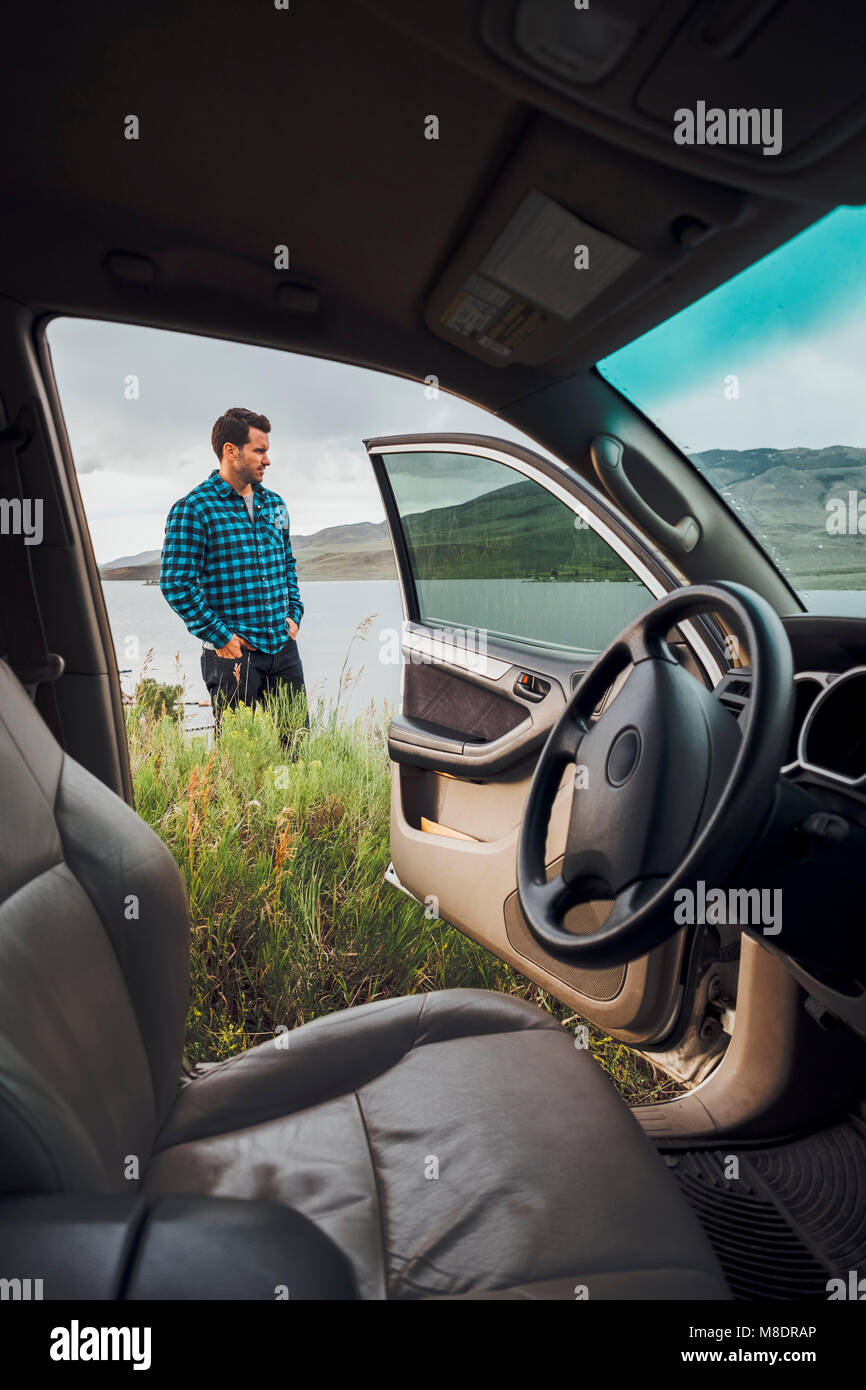 Metà uomo adulto in piedi accanto al serbatoio di Dillon, vista attraverso la macchina parcheggiata, Silverthorne, Colorado, STATI UNITI D'AMERICA Foto Stock