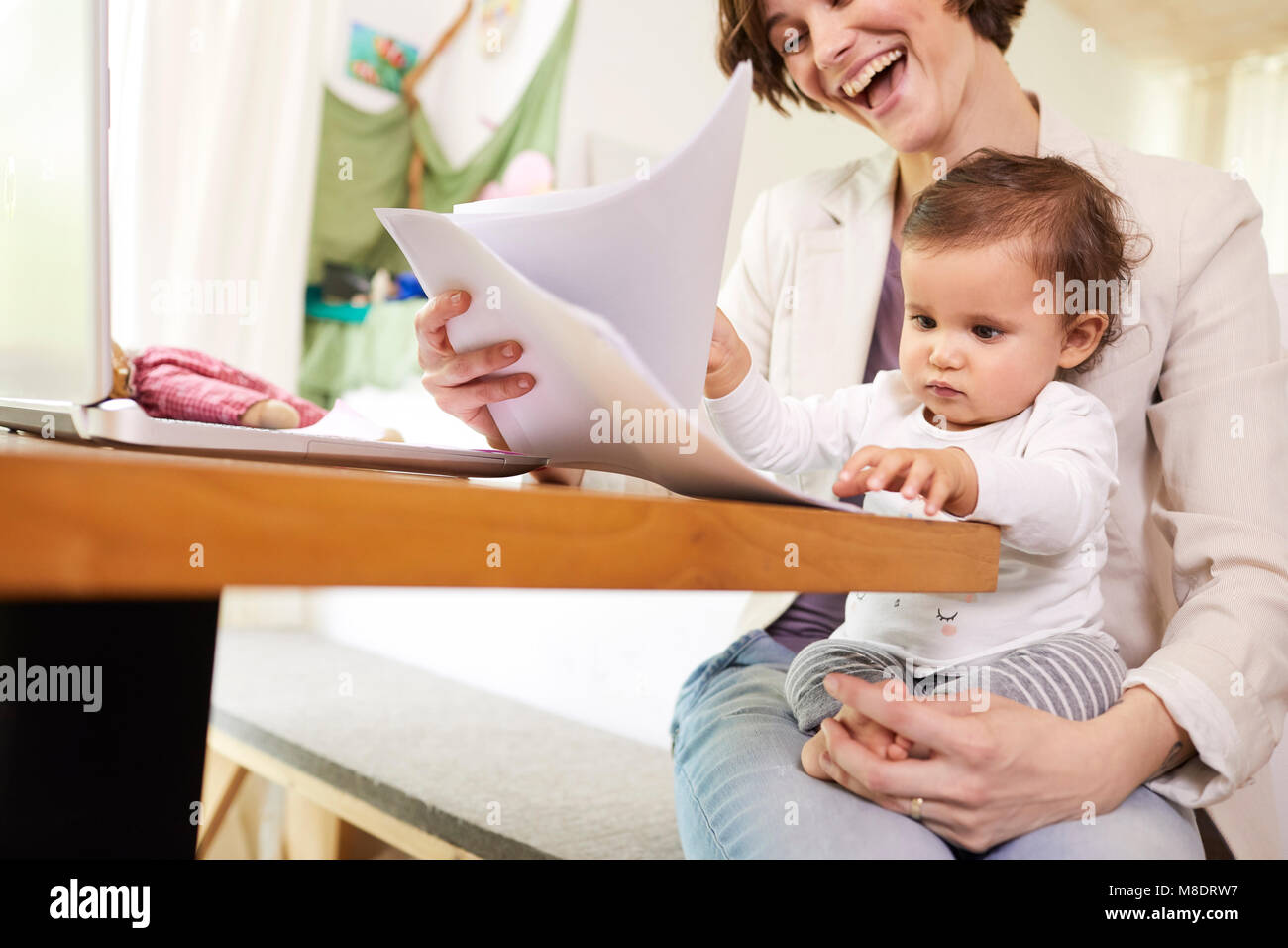 Madre guardando la documentazione con baby ragazza seduta sul suo giro Foto Stock