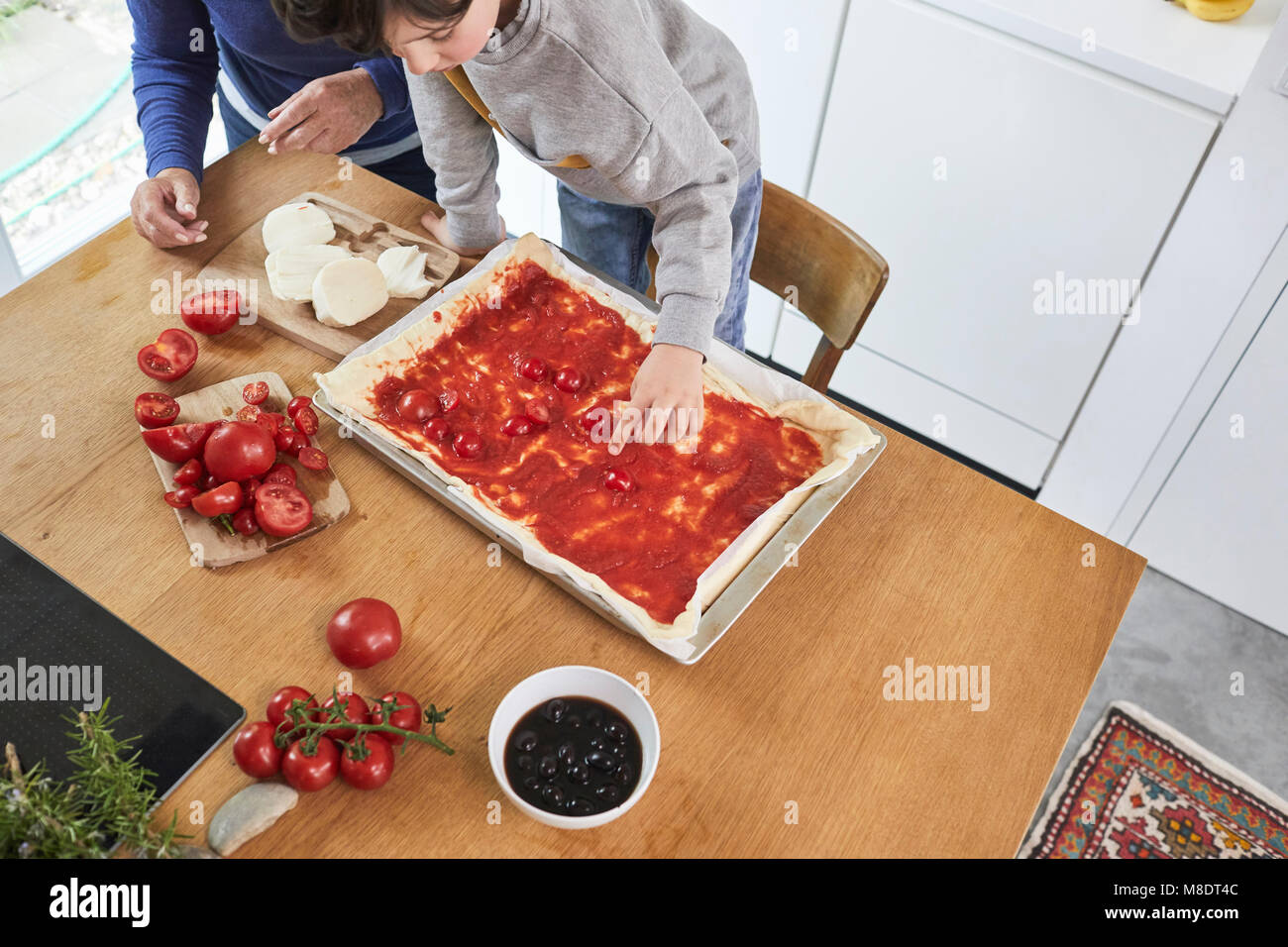Nonna e nipote rendendo la pizza in cucina, vista in elevazione Foto Stock