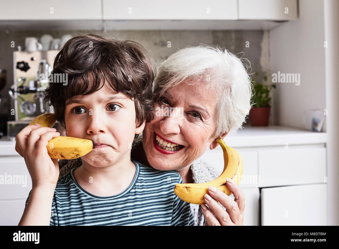 Nonna e nipote ingannare intorno, utilizzando le banane come telefoni, ridendo Foto Stock