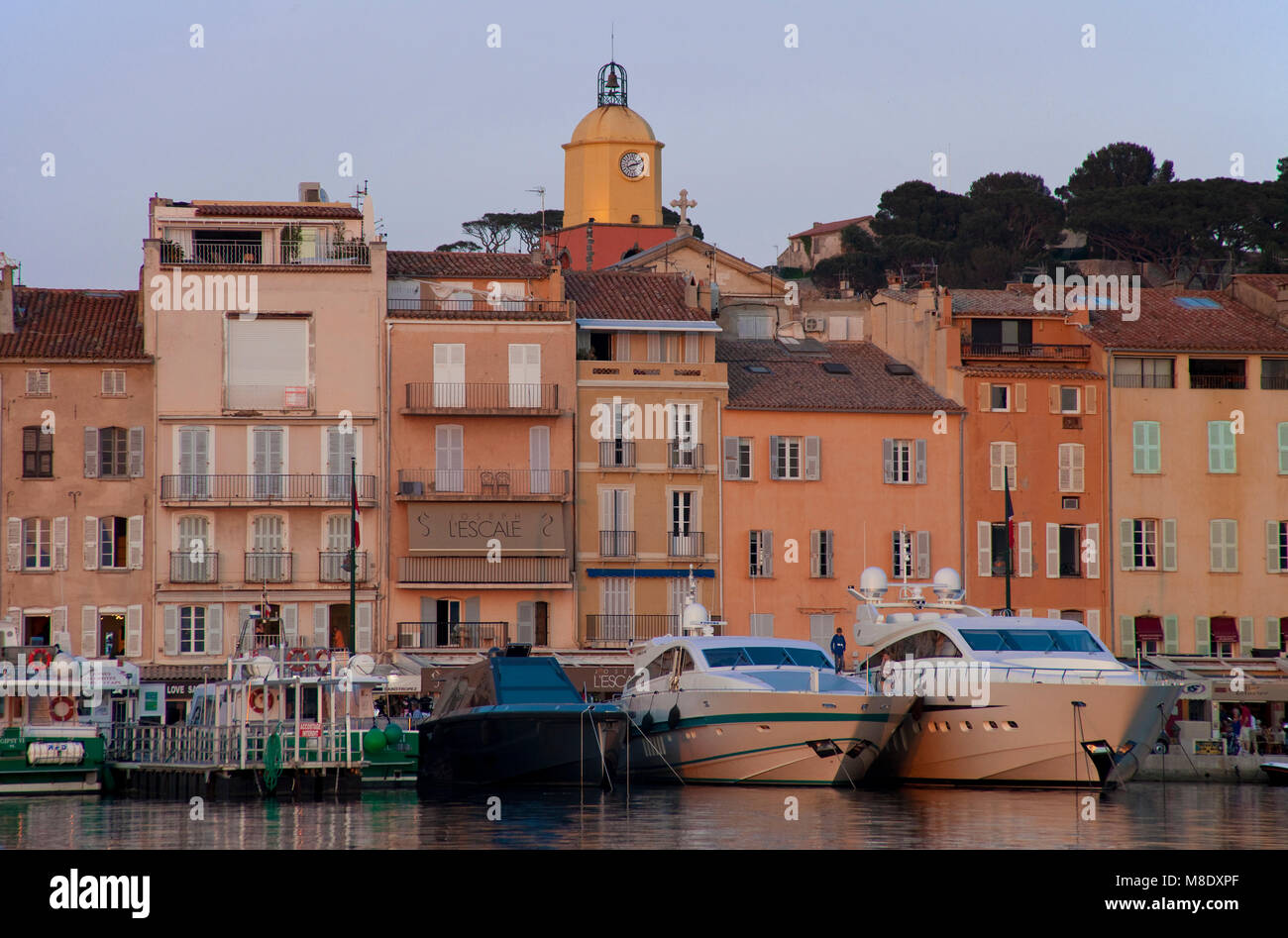 Atmosfera serale presso il porto di Saint-Tropez, yacht di lusso in banchina, dietro il passeggiare lungomare, riviera francese, il sud della Francia, Cote d'Azur, in Francia Foto Stock