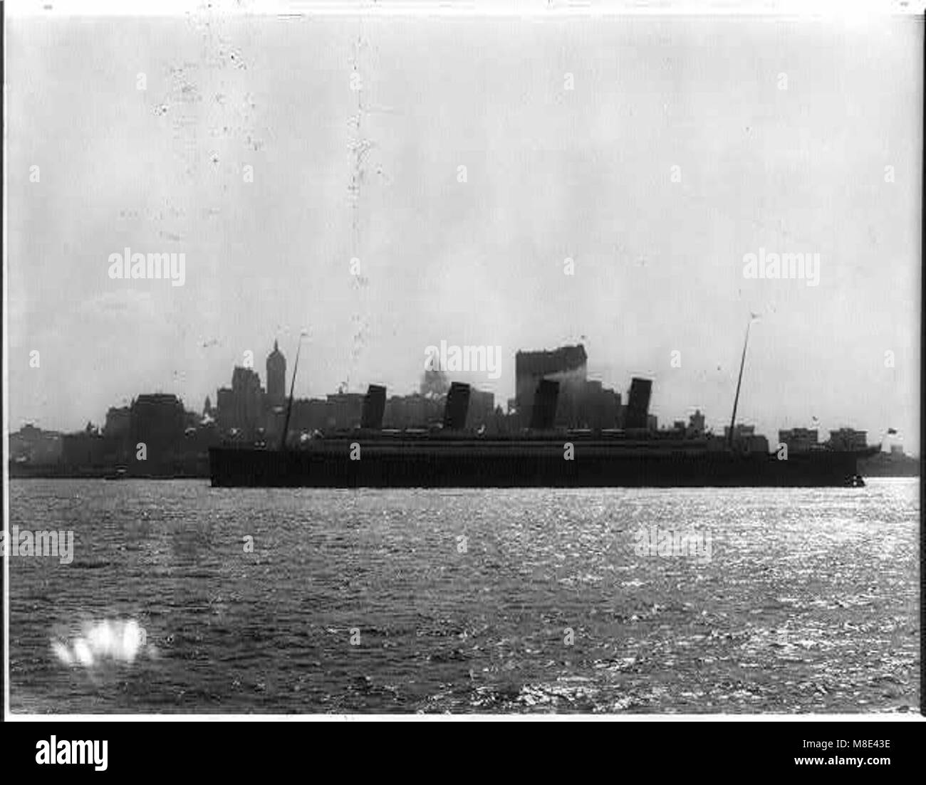 Una vista a tutta lunghezza della S.S. Olympic nel 1911, con lo skyline di New York sullo sfondo, che mostra l'iconico transatlantico e la sua importanza nel viaggio marittimo all'inizio del XX secolo. Foto Stock