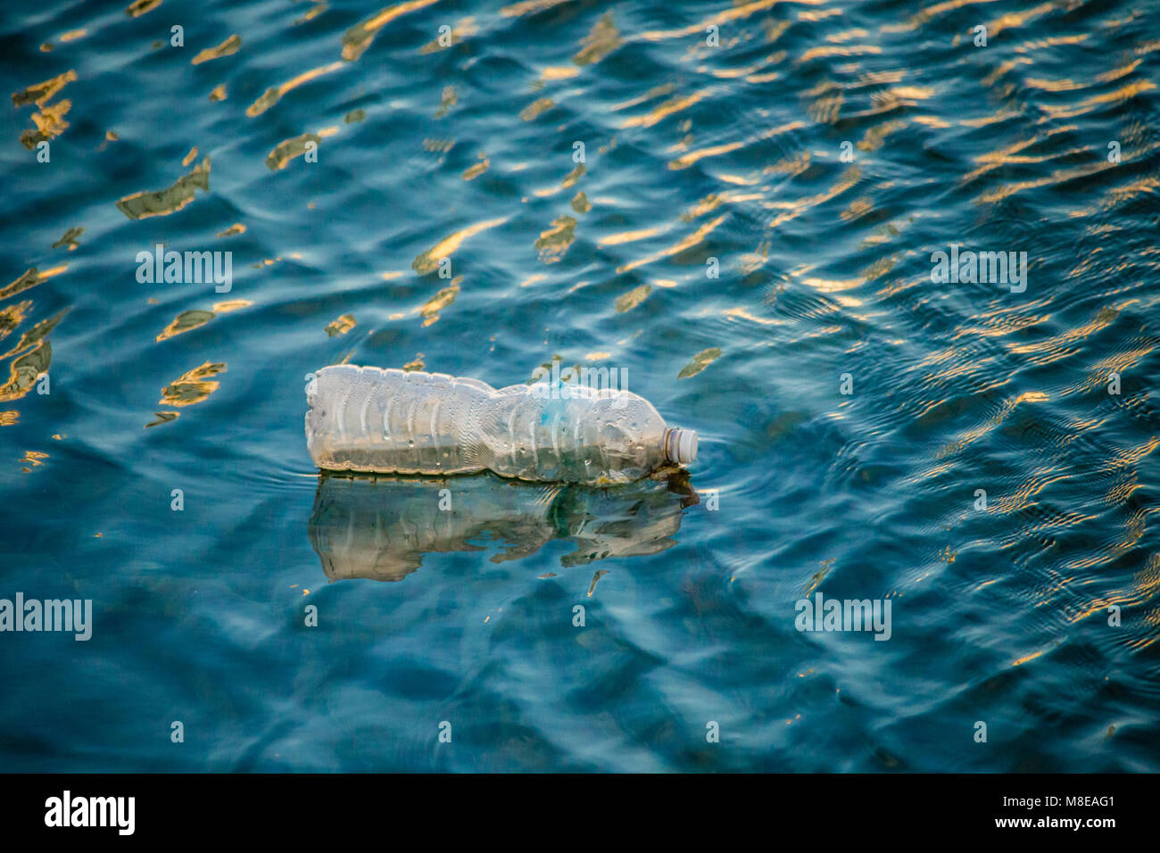 Floating bottiglia di plastica in acqua di ondulazione Foto Stock