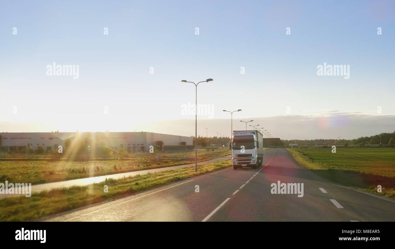 White Semi carrello con carico rimorchio rigidi su un'autostrada con bellissimo panorama soleggiato in background. Foto Stock