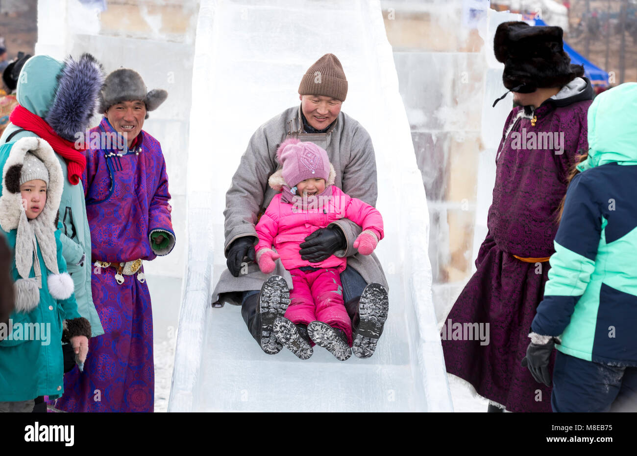 Hatgal, Mongolia, 4 Marzo 2018: il mongolo uomo venire giù una diapositiva con sua figlia Foto Stock