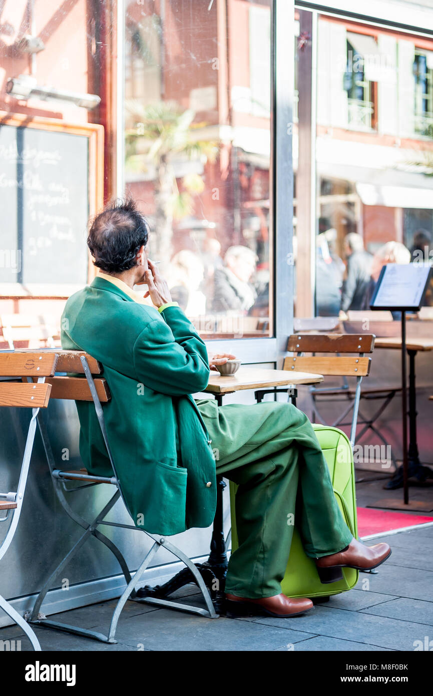 Molto elegante gentleman indossando un recupero verde corrispondente ensemble si rilassa in vecchio stile cafe a Nizza Francia in inverno. Foto Stock