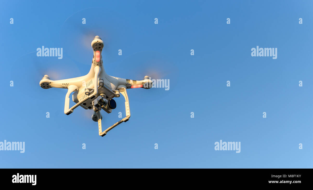 Drone in volo di fronte a un cielo blu Foto Stock