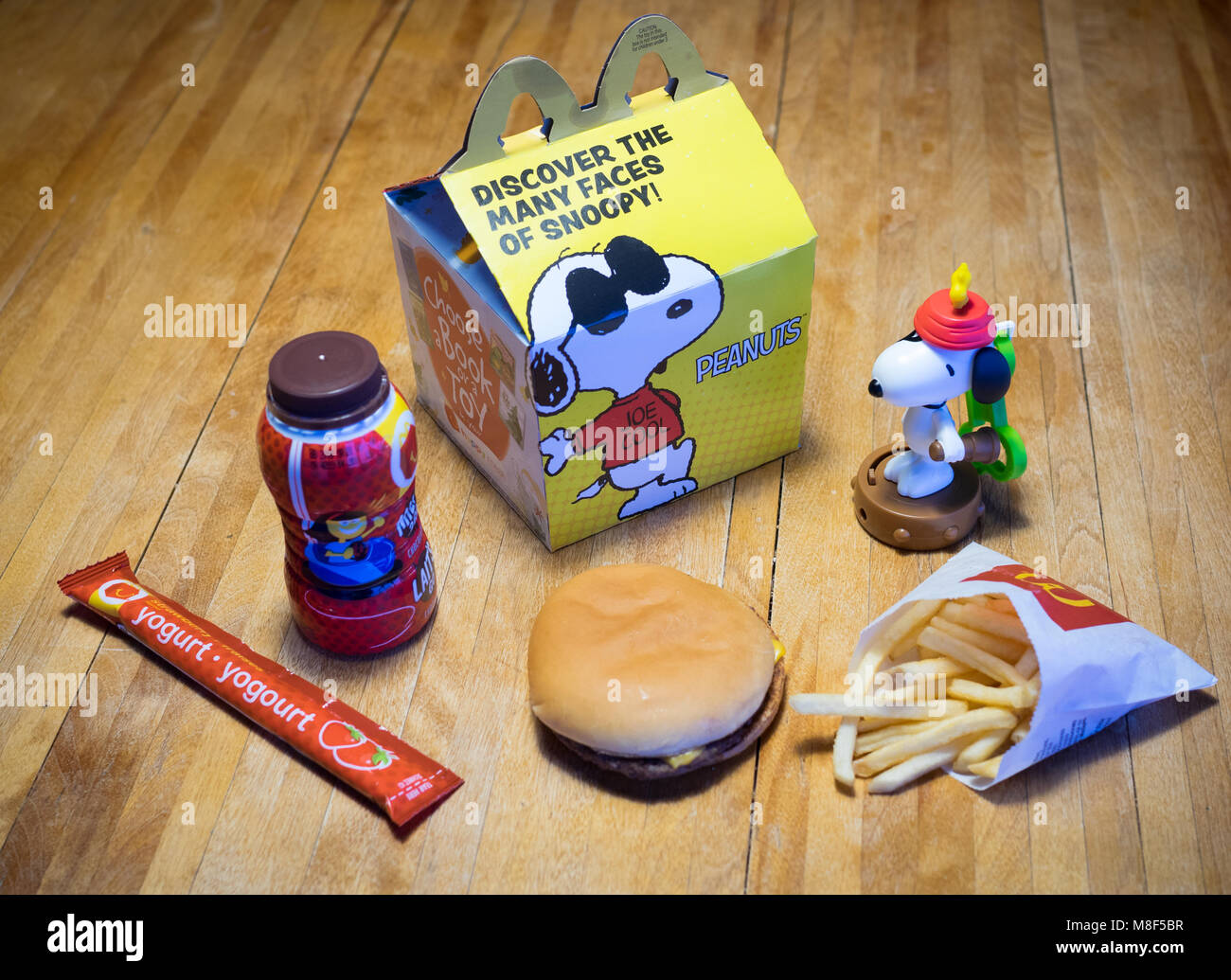 Un McDonald's Happy Meal con un cheeseburger, patatine fritte, cioccolato al latte, yogurt tubo e Snoopy giocattolo. Foto Stock