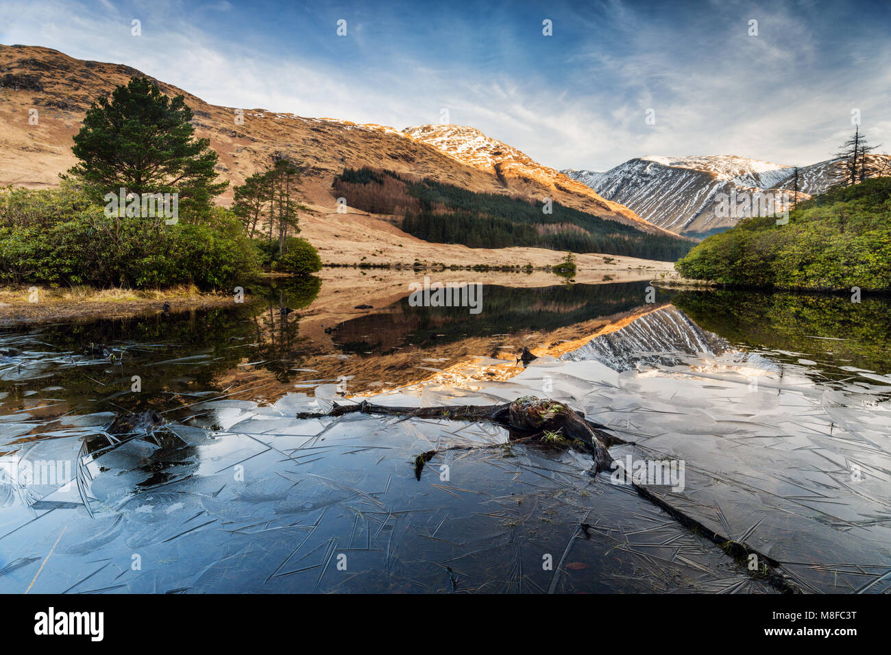 Riflessioni a Lochan Urr su una chiara e fredda soleggiata giornata di primavera, Glen Etive, Highlands scozzesi, Regno Unito, Scozia Foto Stock