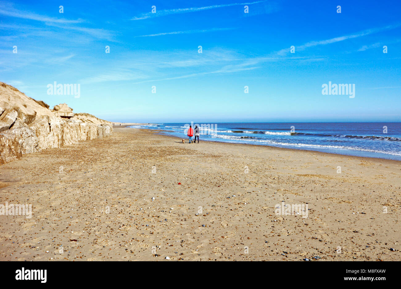 Due signore a piedi un cane a est la Spiaggia di Norfolk a Winterton-on-Sea, Norfolk, Inghilterra, Regno Unito, Europa. Foto Stock