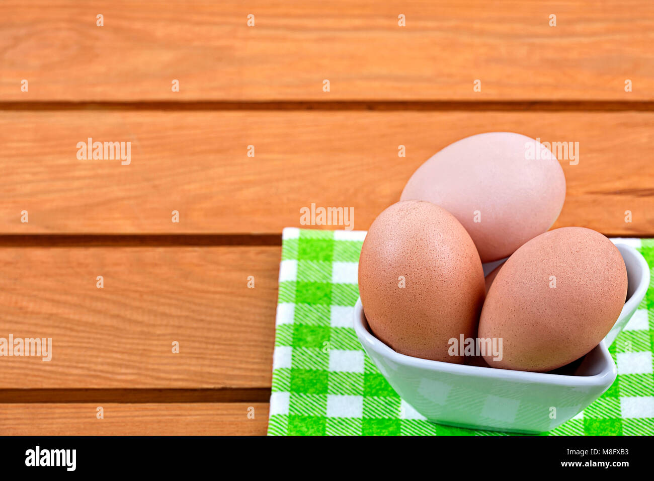 Le uova in una terrina di porcellana su un sfondo di legno Foto Stock