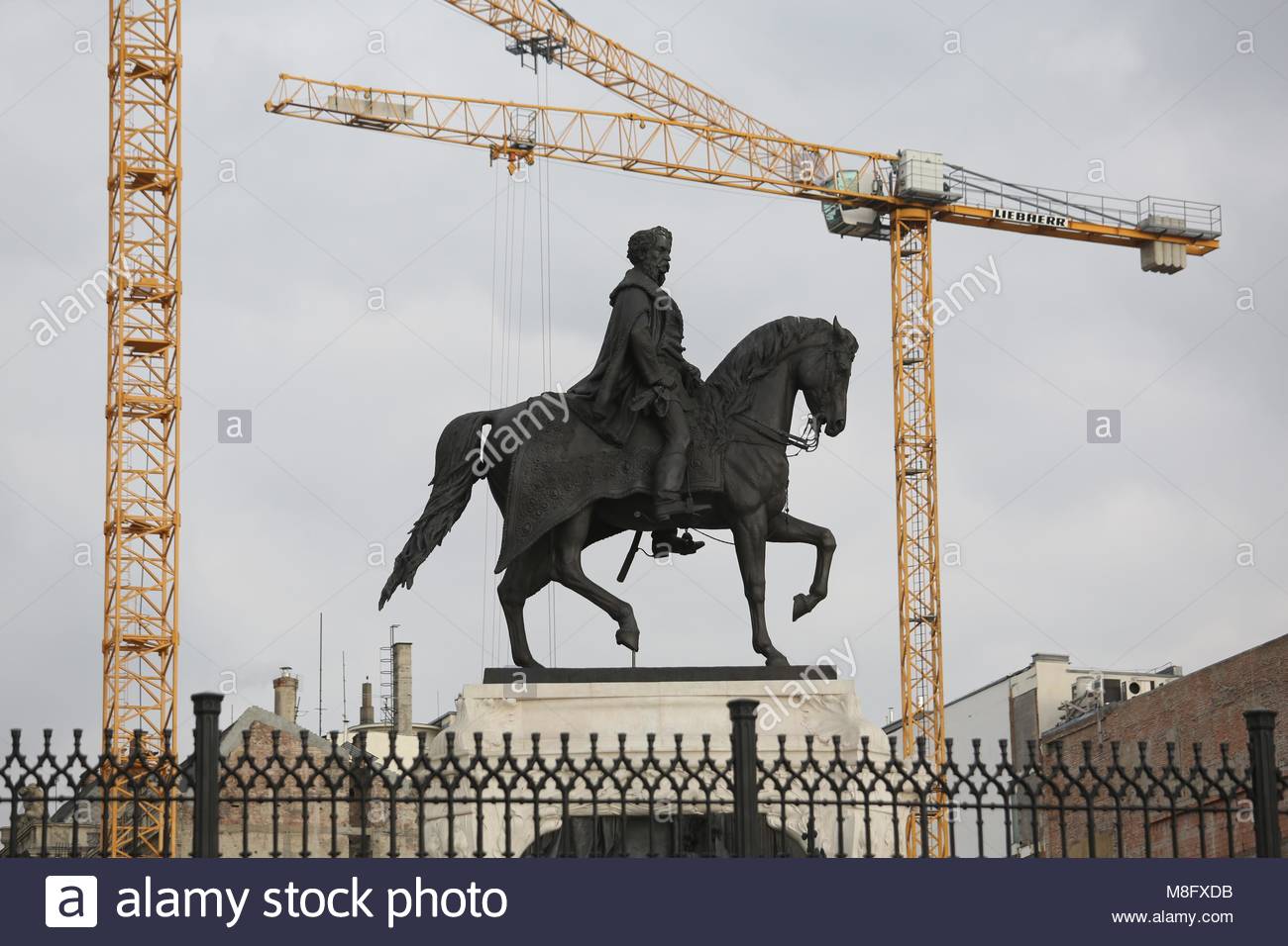 Una statua vicino al parlamento di Budapest è circondato da gru a lavorare sugli sviluppi nei pressi del sito. Foto Stock