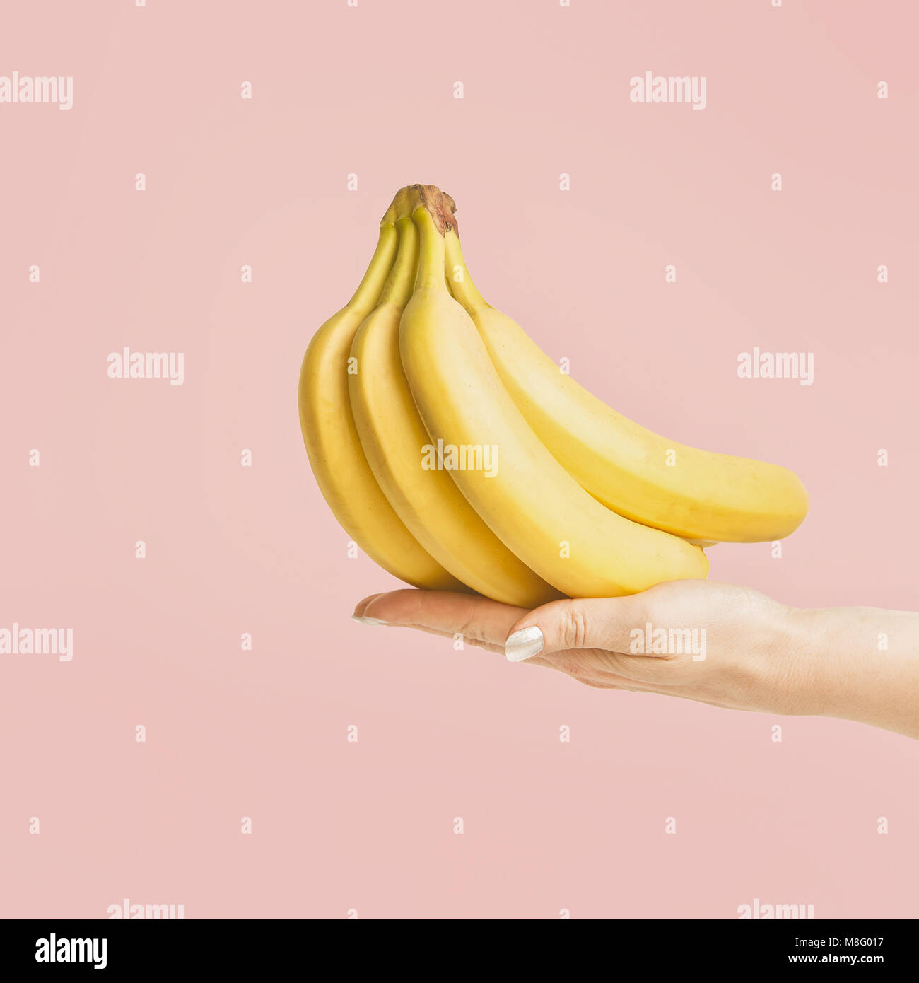 Femmina tenuta a mano mazzo di banane a pastello sfondo rosa, vista frontale Foto Stock