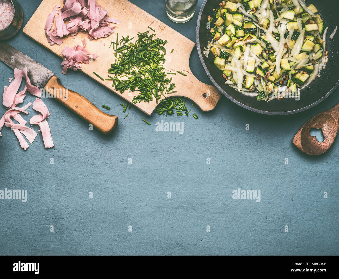 Gustose le zucchine e prosciutto piatto nel recipiente di cottura sul tavolo da cucina con ingredienti, vista dall'alto Foto Stock
