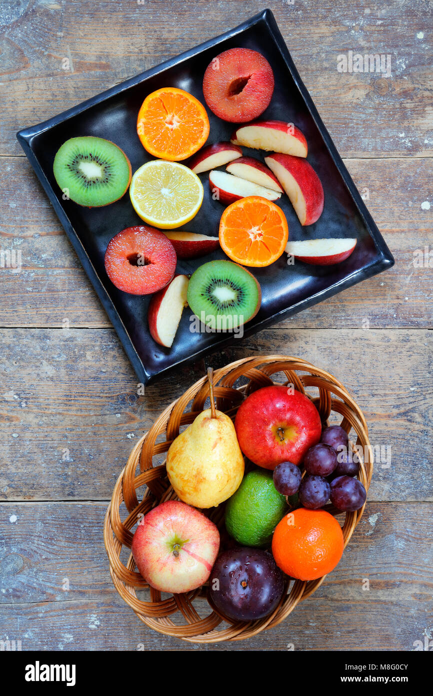 E tutta la frutta a fette di mele, calce, limone, pere e prugne su tavola in legno rustico - verticale in modalità verticale Foto Stock
