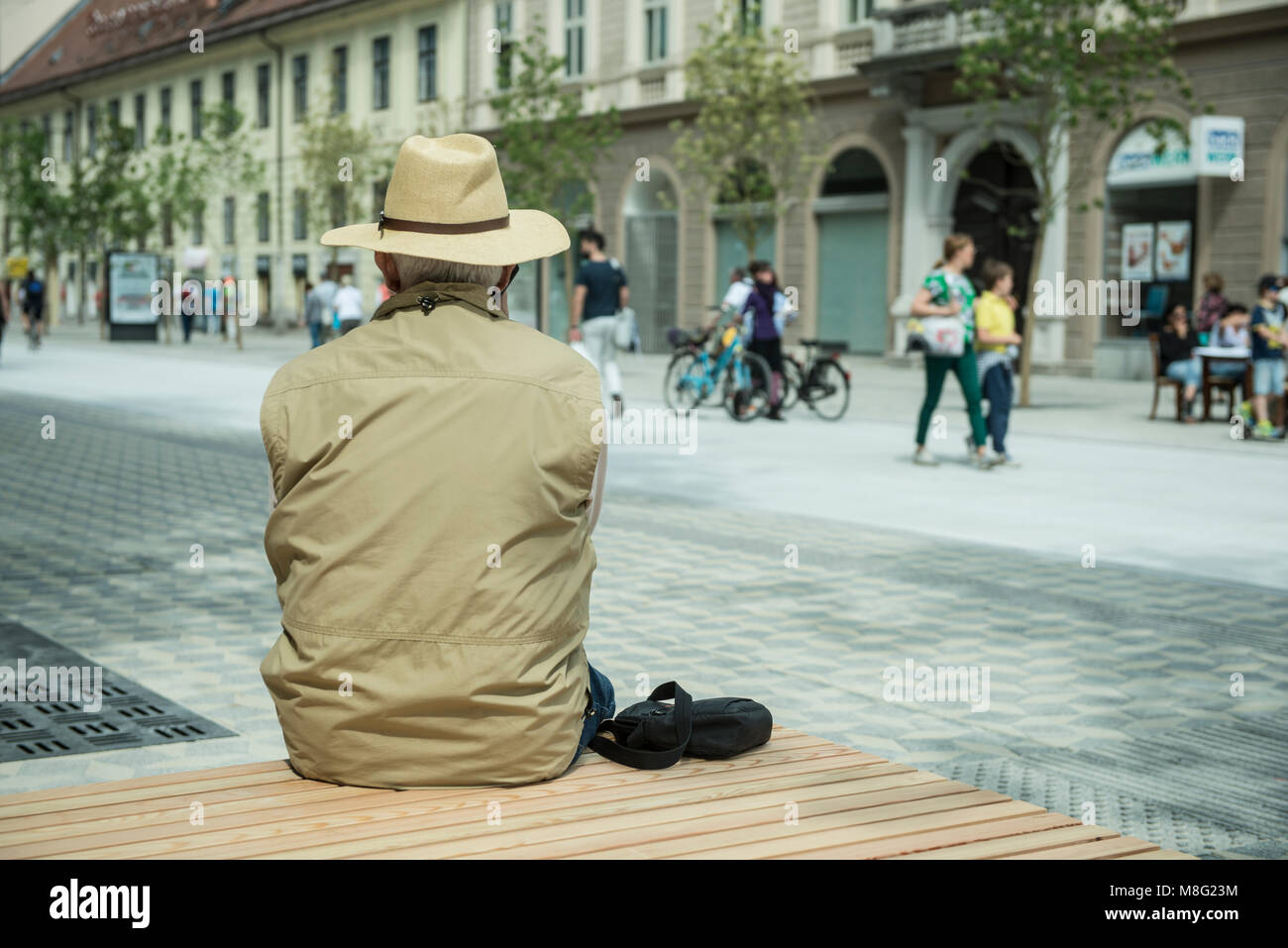 Un uomo anziano seduto sul banco in strada Foto Stock