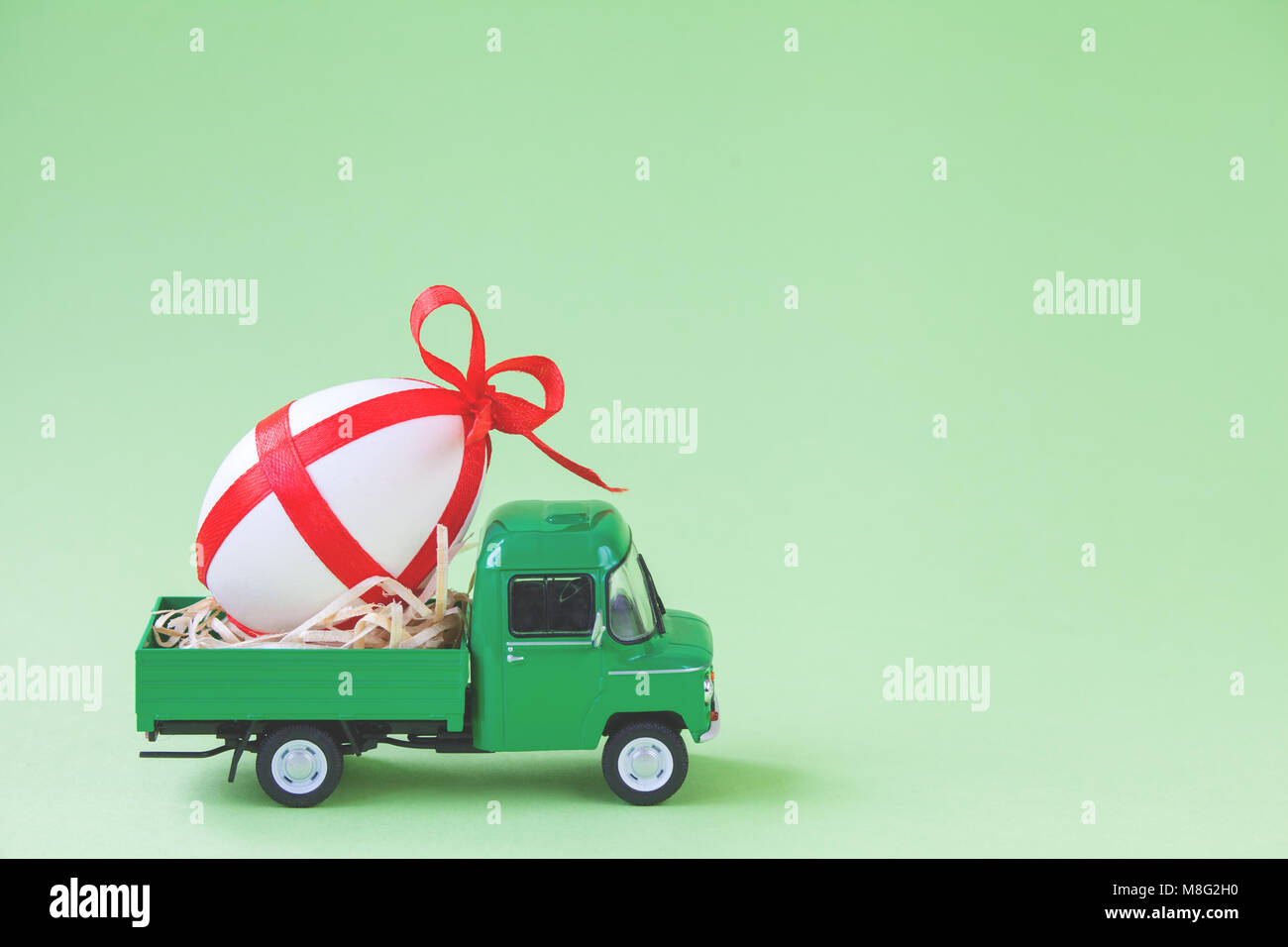 Verde giocattolo di prelievo che trasportano uno decorato uovo di pasqua. Foto Stock
