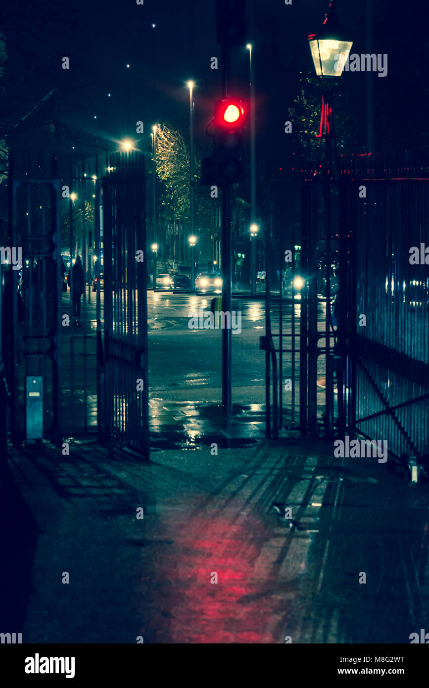 Strada di notte sotto la pioggia con il semaforo rosso colata di un sangue come riflessione sul marciapiede, South Kensington, London, Regno Unito Foto Stock