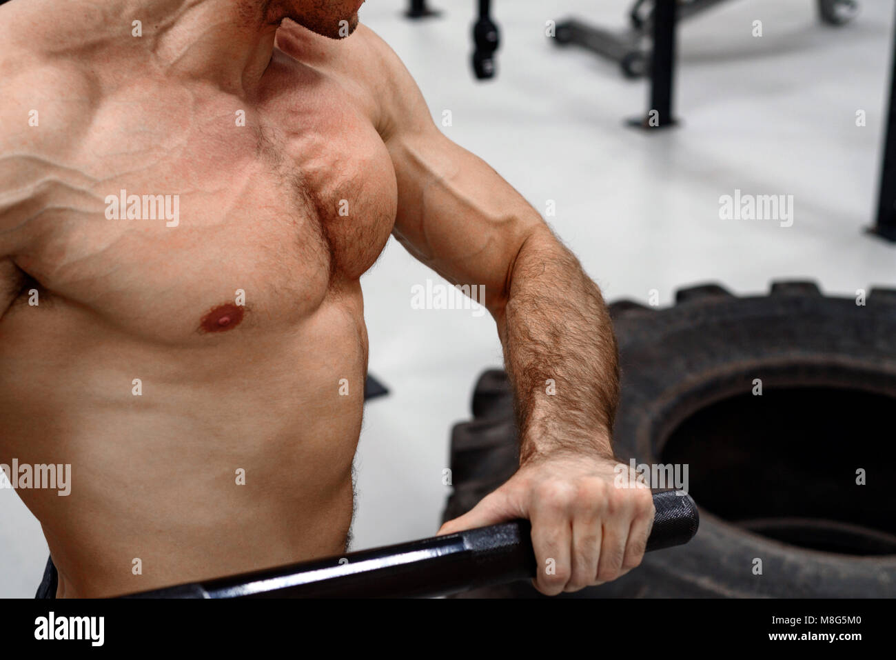 Uomo con una mazza e il pneumatico. Centro fitness Foto Stock