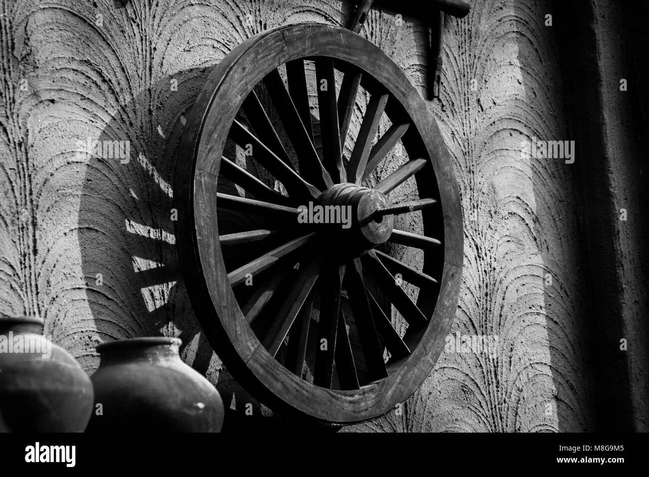 Vecchio appoggiate appoggiata contro la parete di fango in un villaggio in India Foto Stock