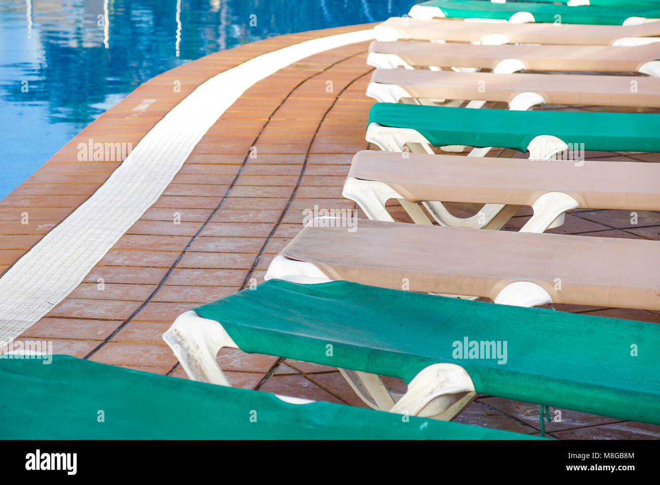 Hotel piscina vuota Rattan lettini vicino alla piscina con blu di calme acque cristalline e la pavimentazione in calcestruzzo piano Foto Stock