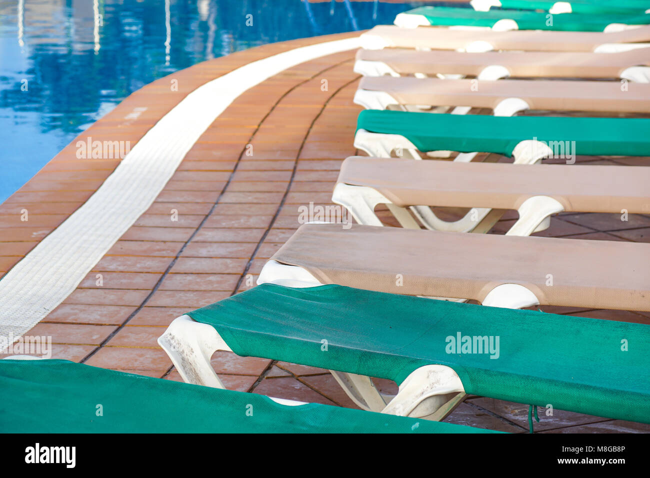 Hotel piscina vuota Rattan lettini vicino alla piscina con blu di calme acque cristalline e la pavimentazione in calcestruzzo piano Foto Stock