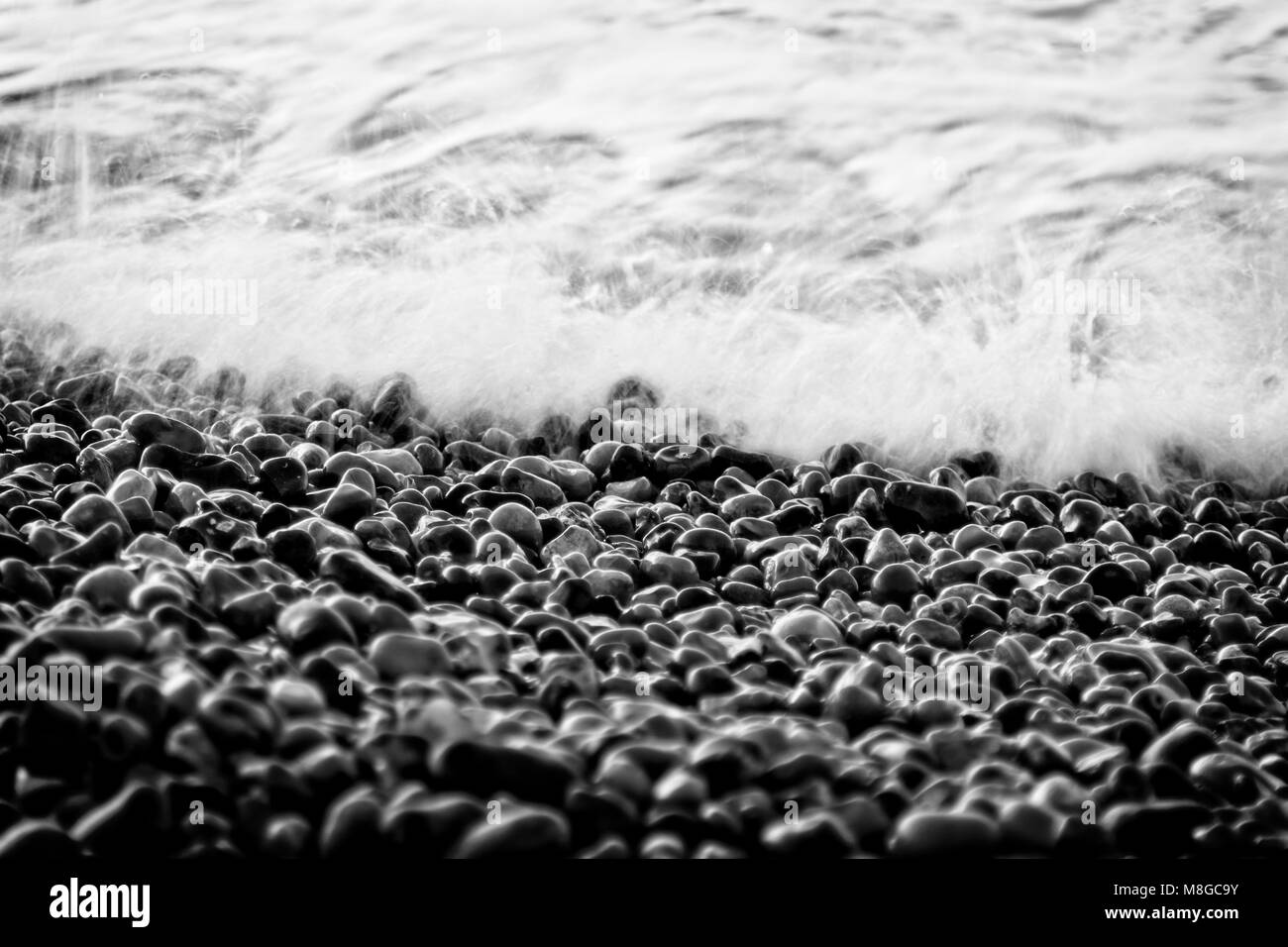 Nero e pietra bianca spiaggia ghiaiosa con white surf Foto Stock