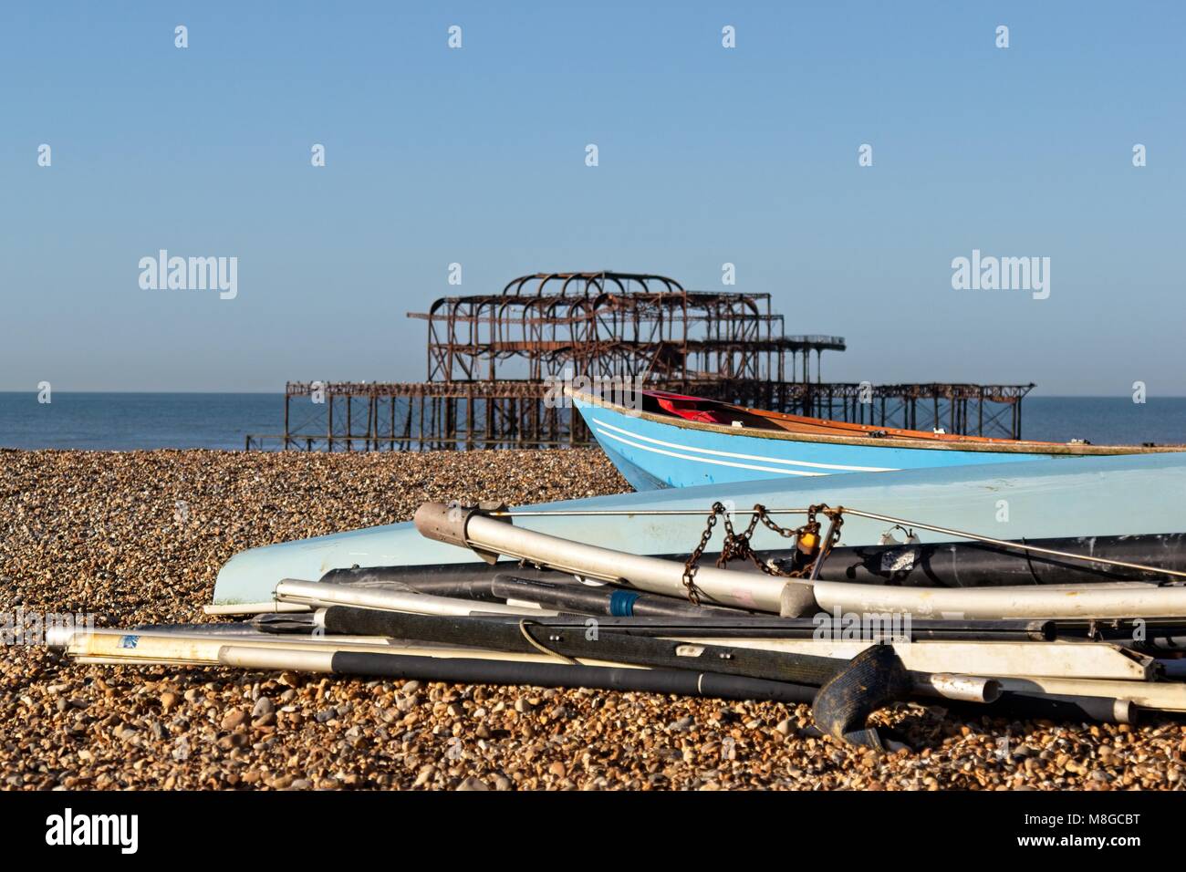 Barche blu sulla spiaggia ghiaiosa di fronte Molo Ovest di Brighton Foto Stock