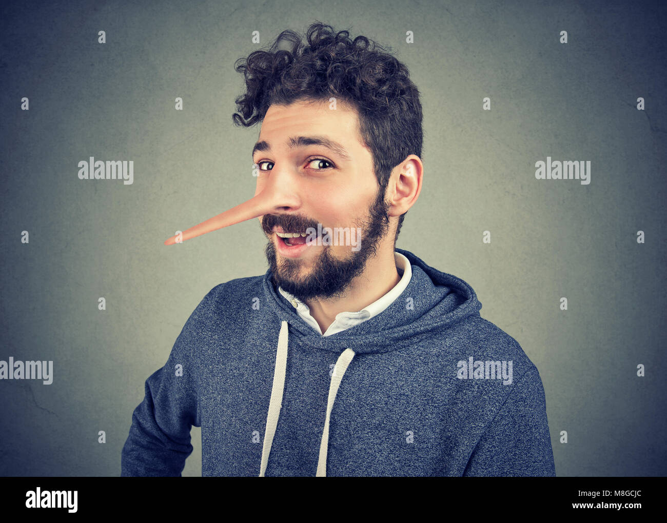 Uomo bugiardo con il naso lungo isolato su sfondo grigio. Le emozioni umane, sentimenti. Foto Stock