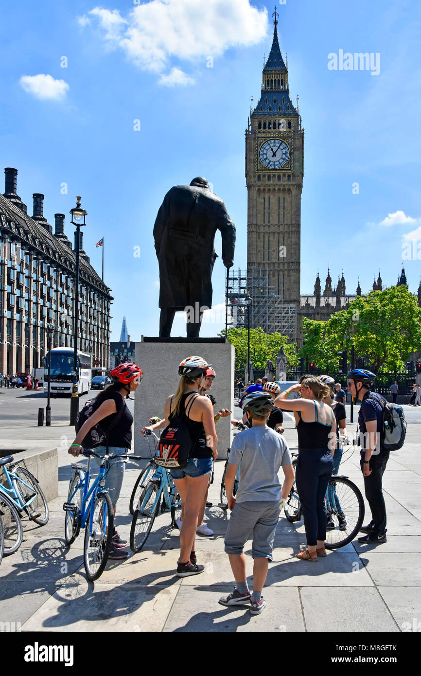 Gruppo di turisti in bicicletta & tour guida accanto a nolo bici riuniti intorno a statua di Sir Winston Churchill in piazza del Parlamento Big Ben Londra Inghilterra REGNO UNITO Foto Stock