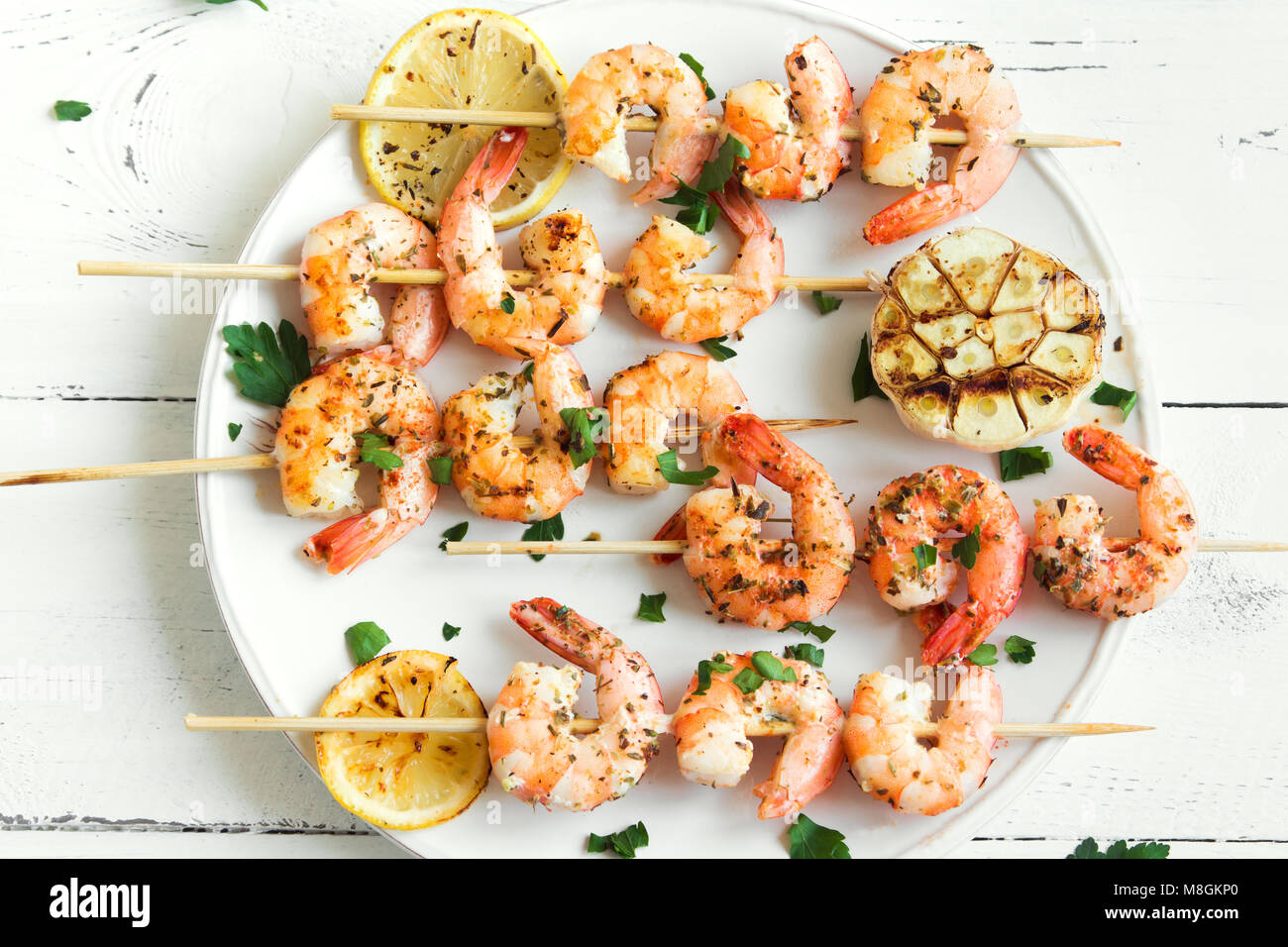 Grigliata di gamberi spiedini. Frutti di mare, shelfish. Gamberi spiedini con spezie e erbe aromatiche fresche in bianco sullo sfondo di legno, copia dello spazio. Gamberi b Foto Stock