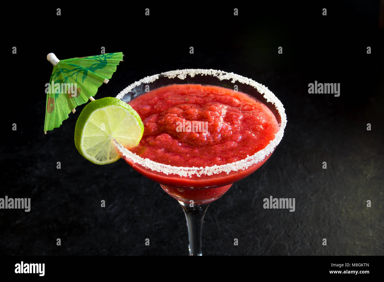 Strawberry Margarita Сocktail con calce su nero tavolo di pietra, copia dello spazio. Congelati o Margarita Daiquiry Cocktail. Foto Stock