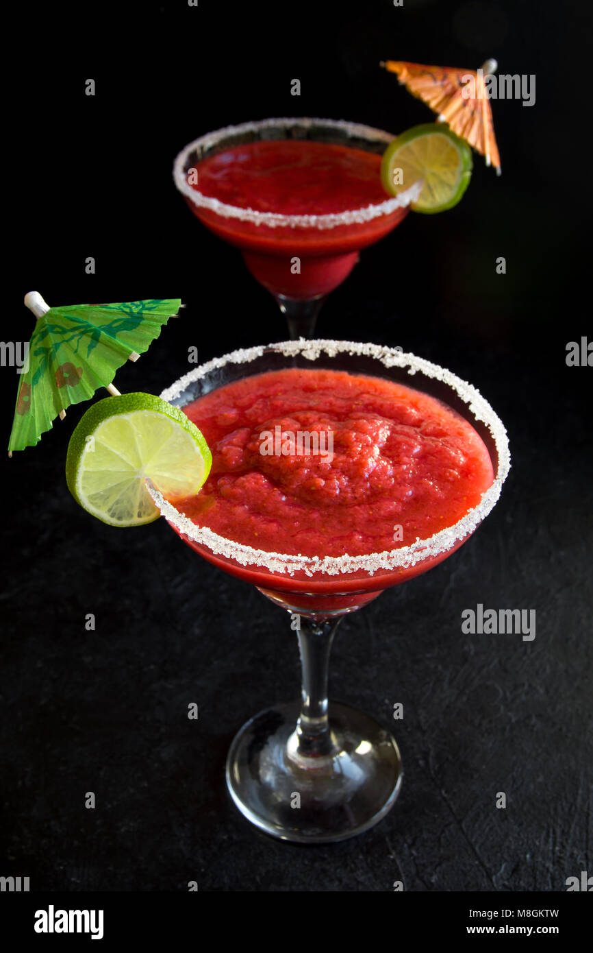 Strawberry Margarita Сocktail con calce su nero tavolo di pietra, copia dello spazio. Congelati o Margarita Daiquiry Cocktail. Foto Stock