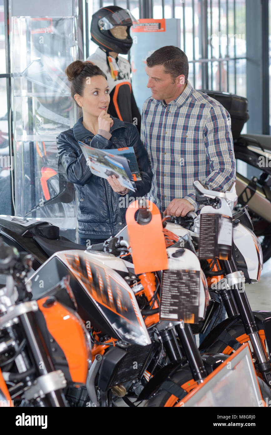 Uomo e donna azienda brochure in motocicletta showroom Foto Stock