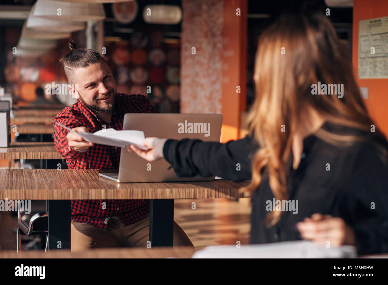 Ridendo imprenditore con documenti a parlare con il suo collega durante la riunione in cafe Foto Stock