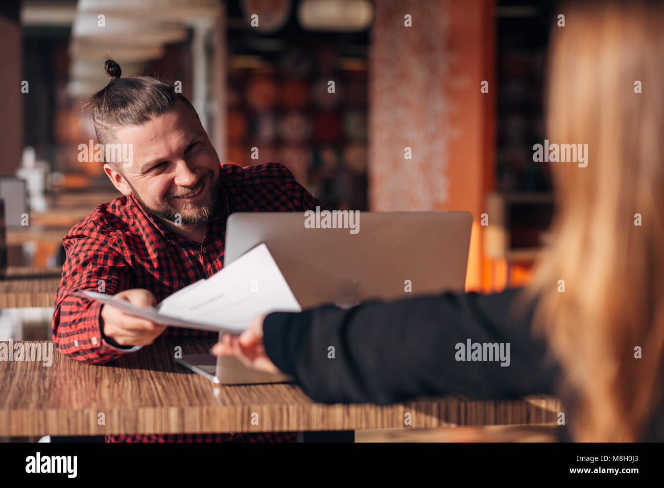 Ridendo imprenditore con documenti a parlare con il suo collega durante la riunione in cafe Foto Stock