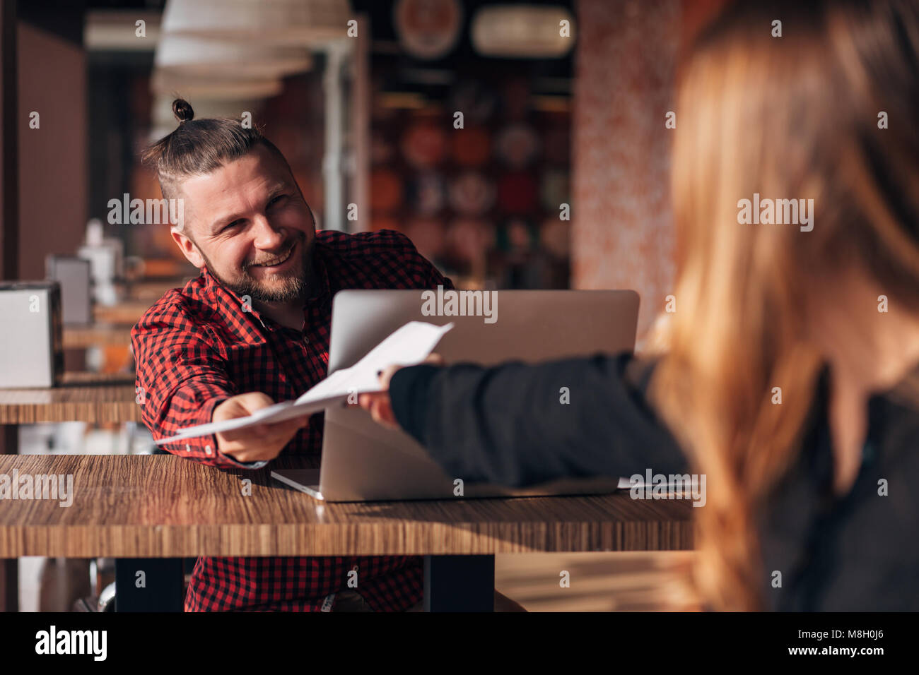 Ridendo imprenditore con documenti a parlare con il suo collega durante la riunione in cafe Foto Stock