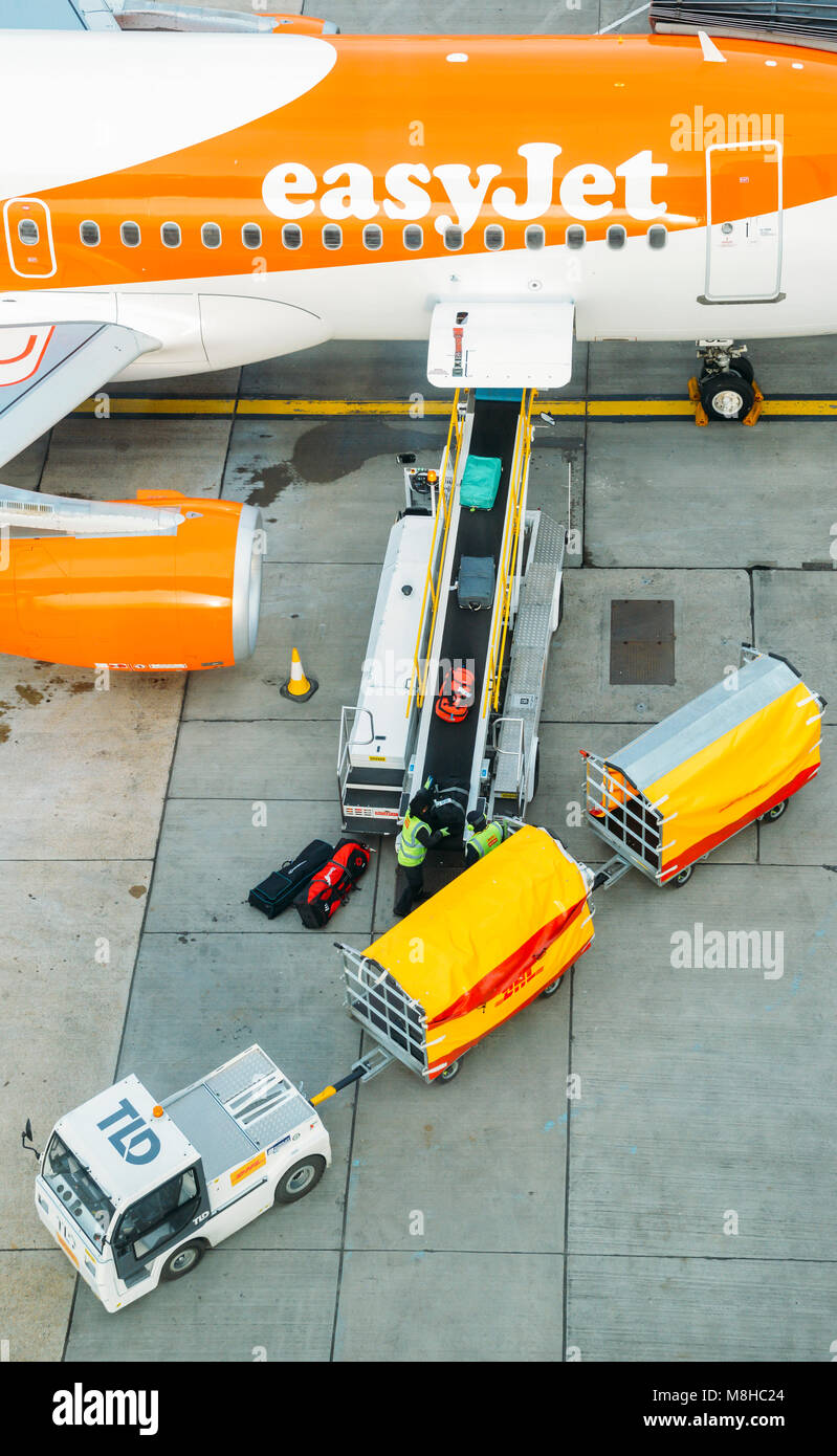 Alta prospettiva di bagagli di prelevare le valigie da un nastro trasportatore collegato a un Airbus A320 aereo easyJet a Londra Gatwick North Terminal Foto Stock