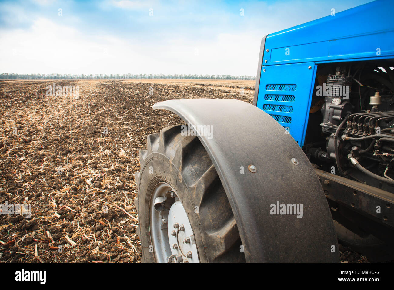 Il vecchio trattore blu close-up in un campo vuoto su una luminosa giornata di sole. Macchine agricole, il lavoro sul campo. Foto Stock
