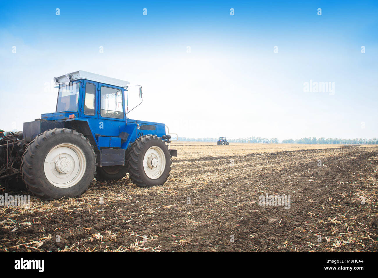Vecchio Blu il trattore in un campo vuoto su una luminosa giornata di sole. Macchine agricole, il lavoro sul campo. Foto Stock