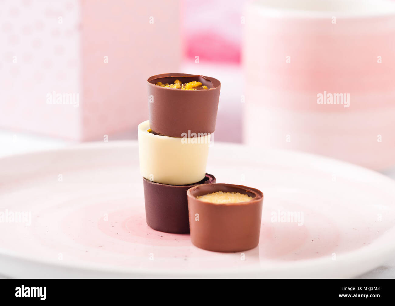 Assortimento di bianco di lusso e cioccolato fondente caramelle varietà sulla piastra di rosa con la coppa e la confezione regalo Foto Stock