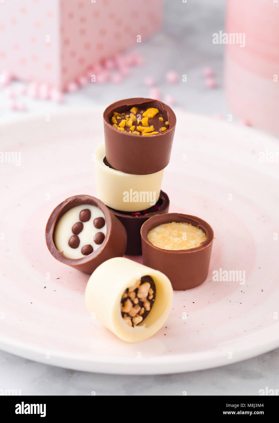 Assortimento di bianco di lusso e cioccolato fondente caramelle varietà sulla piastra di rosa con la coppa e la confezione regalo Foto Stock