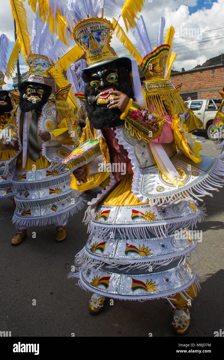 Close-up di uomo in costume tradizionale, maschera e copricapo in giallo e bianco nella parata del festival Foto Stock
