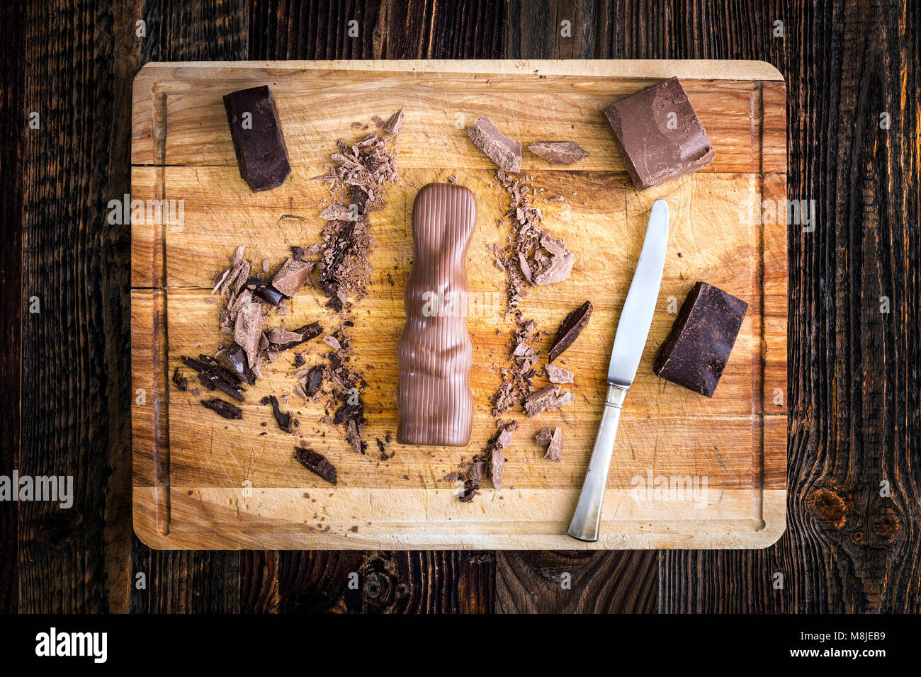 Il coniglio di cioccolato e pezzi grezzi di cioccolato su una tavola di legno Foto Stock