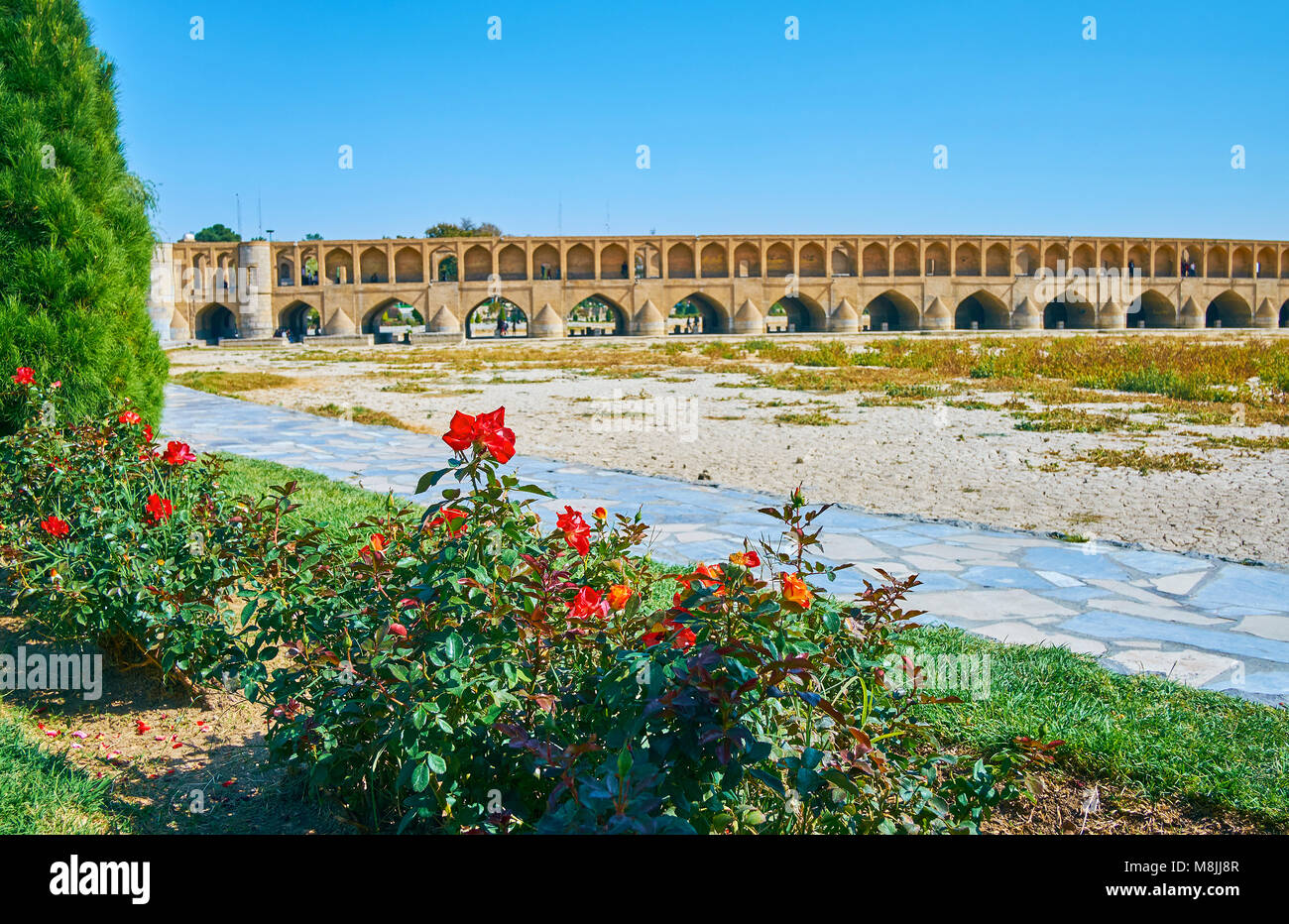 Il centro storico conserva Si-o-se-pol ponte dietro il rosso di cespugli di rose di Koudak park, Isfahan, Iran. Foto Stock