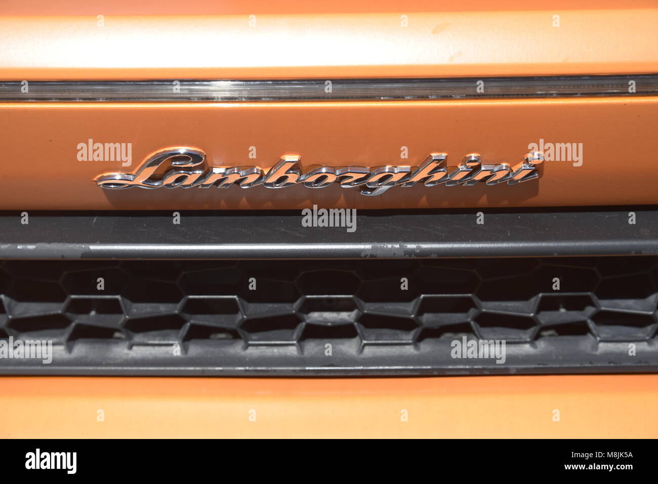Metallo Lamborghini insegne da un arancione Lamborghini Huracan mostra plastica nero grill sotto di esso Foto Stock