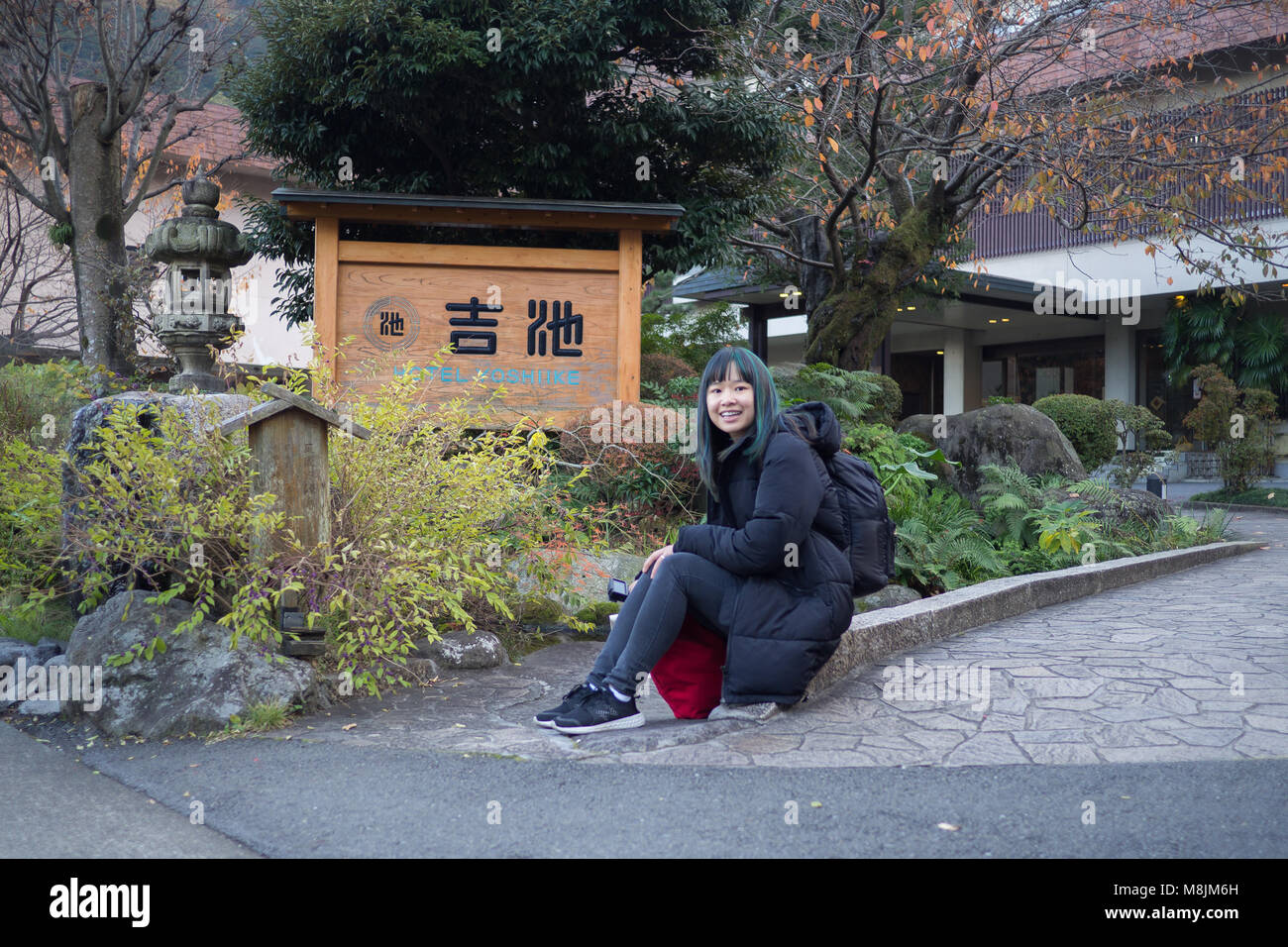 Ragazza seduta all'entrata frontale dell'Hotel Yoshiike Foto Stock