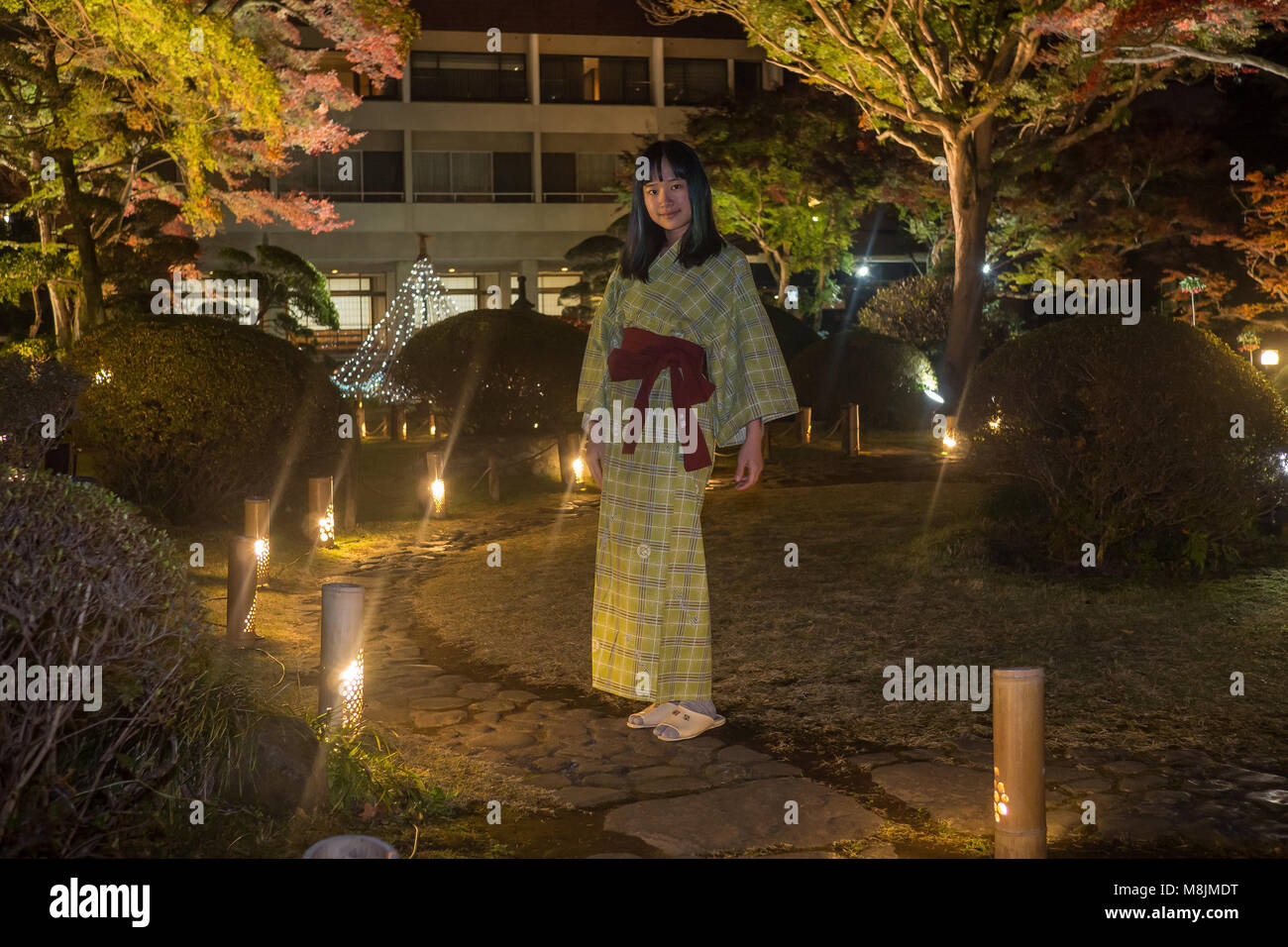 Bella giovane donna in uno yukata passeggiando attraverso un giardino giapponese Foto Stock