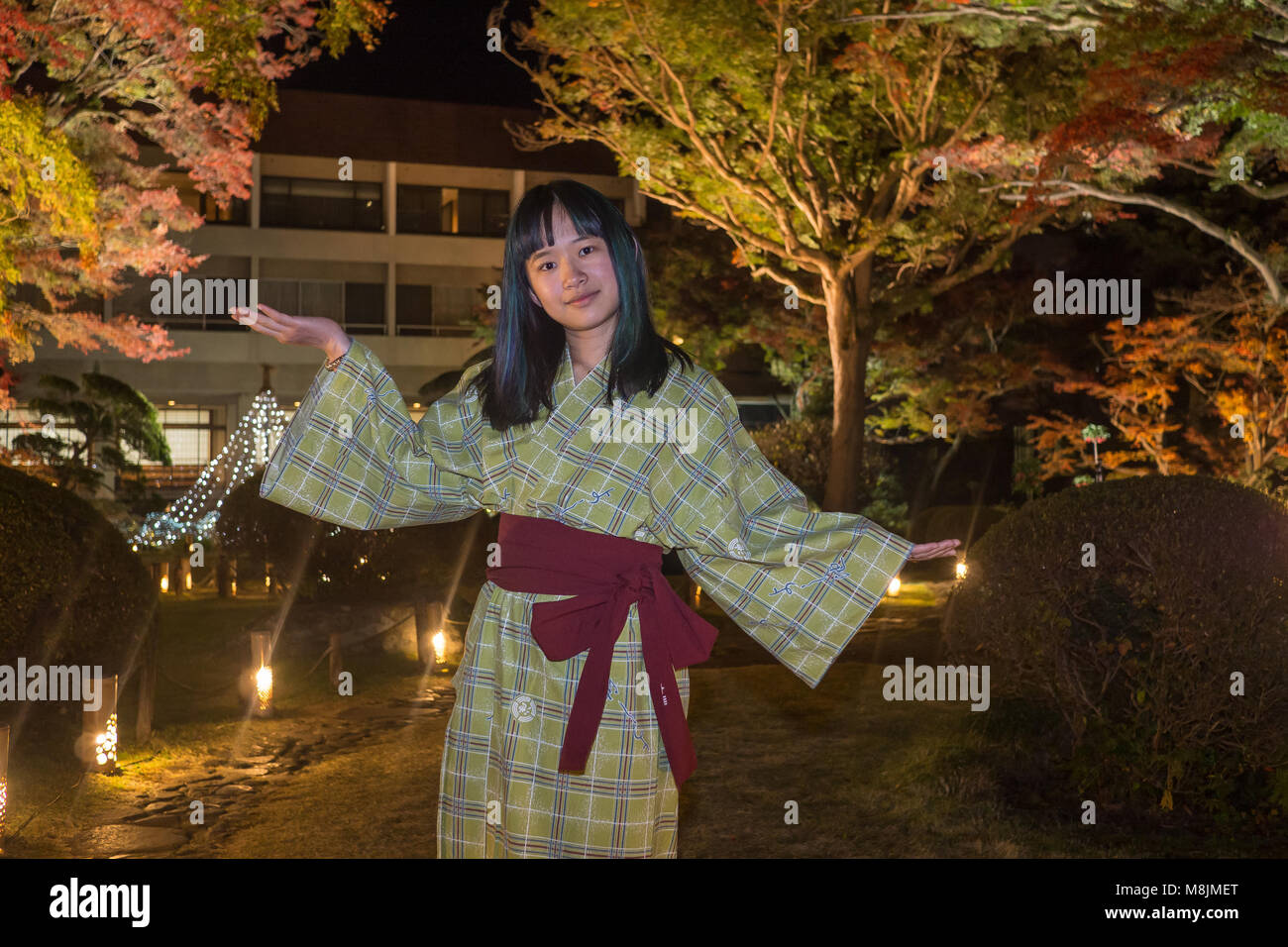Bella giovane donna in uno yukata passeggiando attraverso un giardino giapponese Foto Stock